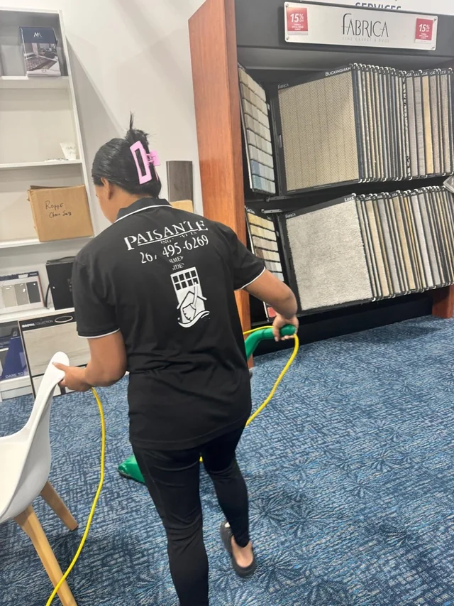 Paisante team member in a branded uniform vacuuming a carpeted retail showroom
