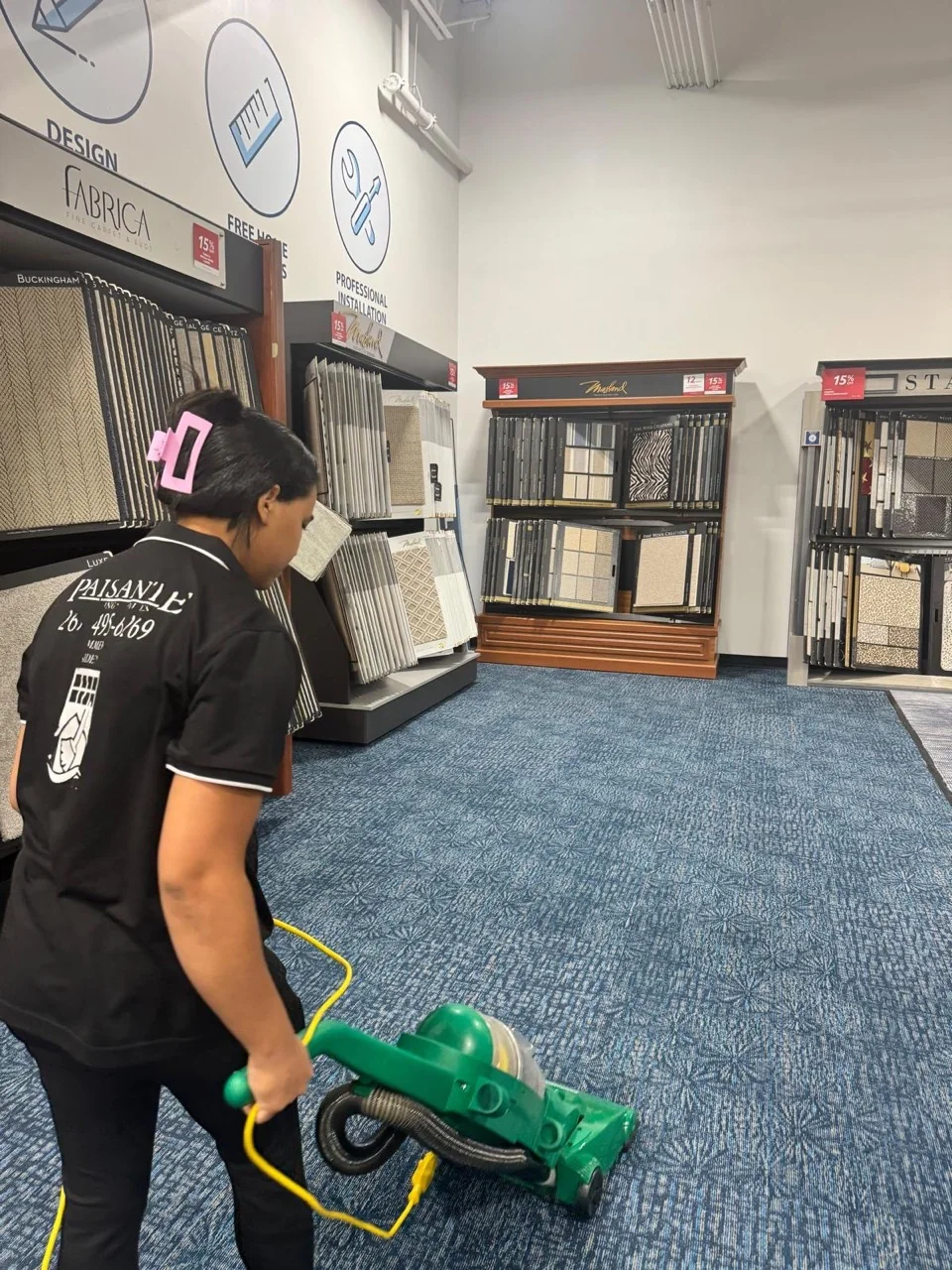 Paisante team member in a branded uniform vacuuming a carpeted retail showroom