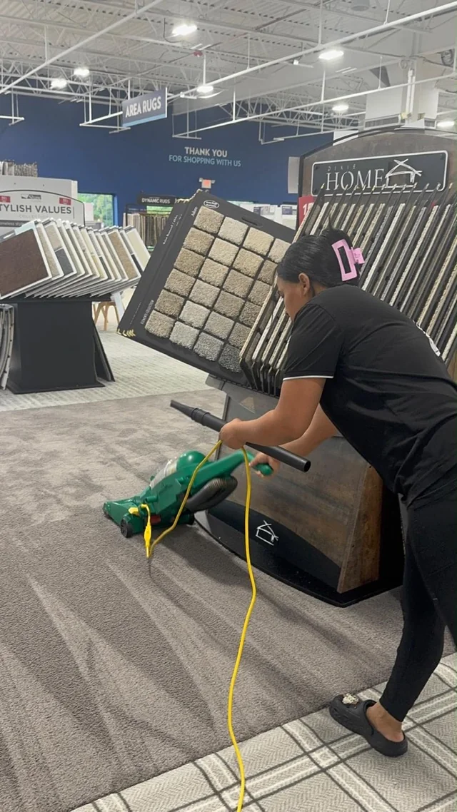 Paisante team member vacuuming beside rug displays in a retail showroom